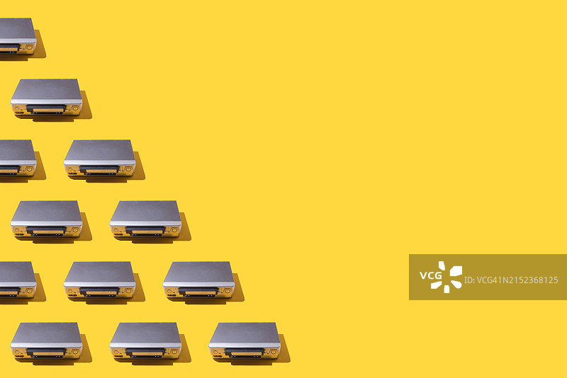 黄色背景下的VHS录像机，左侧插入一半磁带。图像概念：复古，视听，旧且过时。图片素材