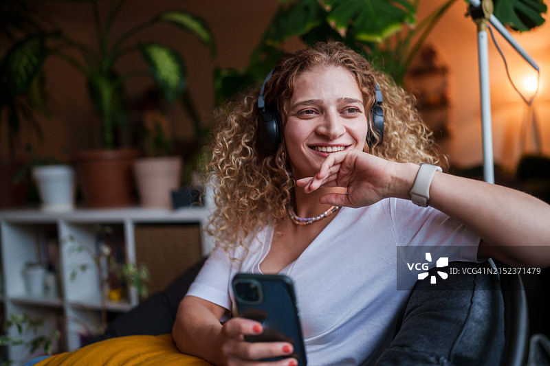 居家女人使用无线耳机和手机的一天图片素材