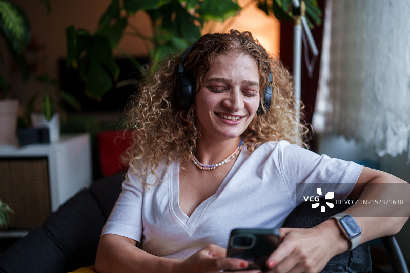 居家女人使用无线耳机和手机的一天图片素材