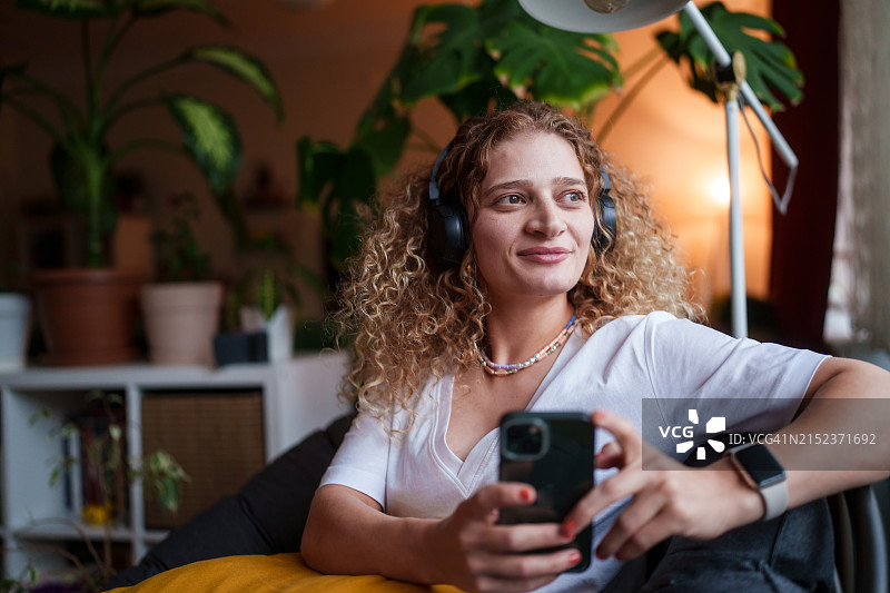 居家女人使用无线耳机和手机的一天图片素材