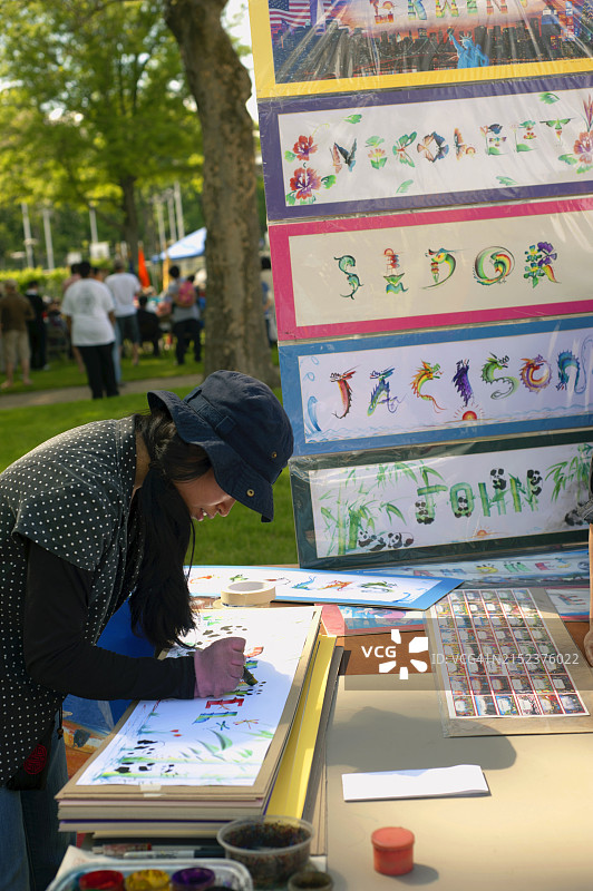 在北亨普斯特德公园的亚裔美国人节上，一位亚裔美国女性用字母和名字创作艺术图片素材