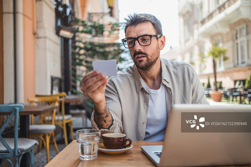 成年男子在咖啡馆用笔记本电脑支付或查看银行账户图片素材