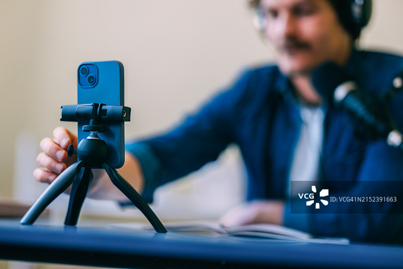年轻人用智能手机在三脚架上拍摄视频博客图片素材