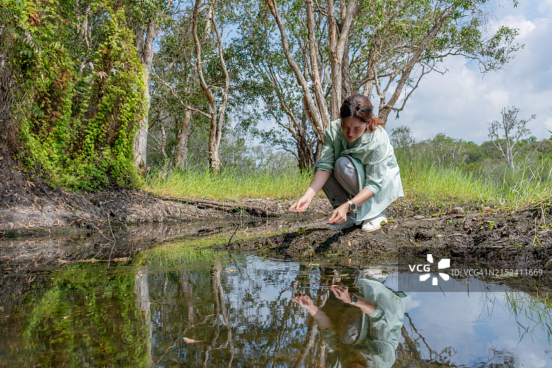 亚裔研究员用镊子提取植物样本，评估水土质量图片素材