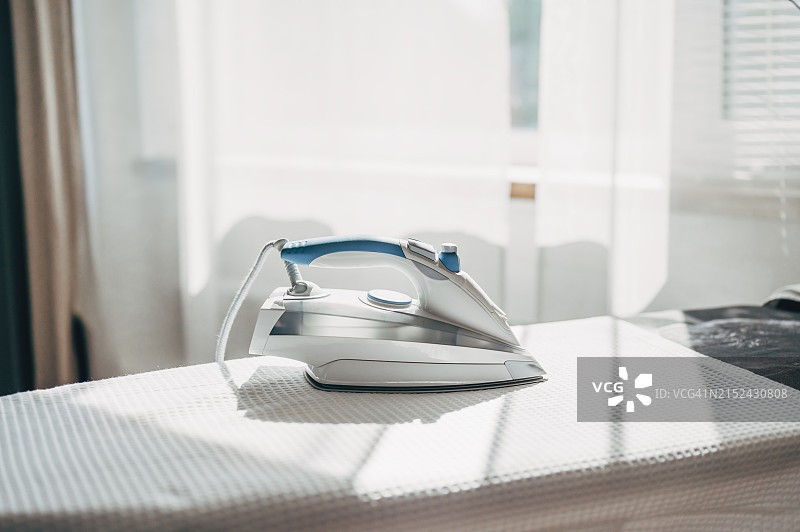 年轻女子用电熨斗熨烫衬衫图片素材