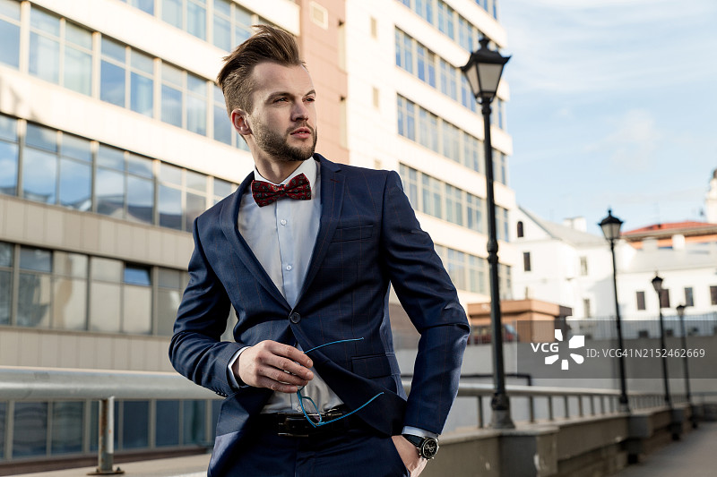 男士在户外穿西装的照片。与帅哥的生活方式摄影。人手里拿着眼镜。图片素材