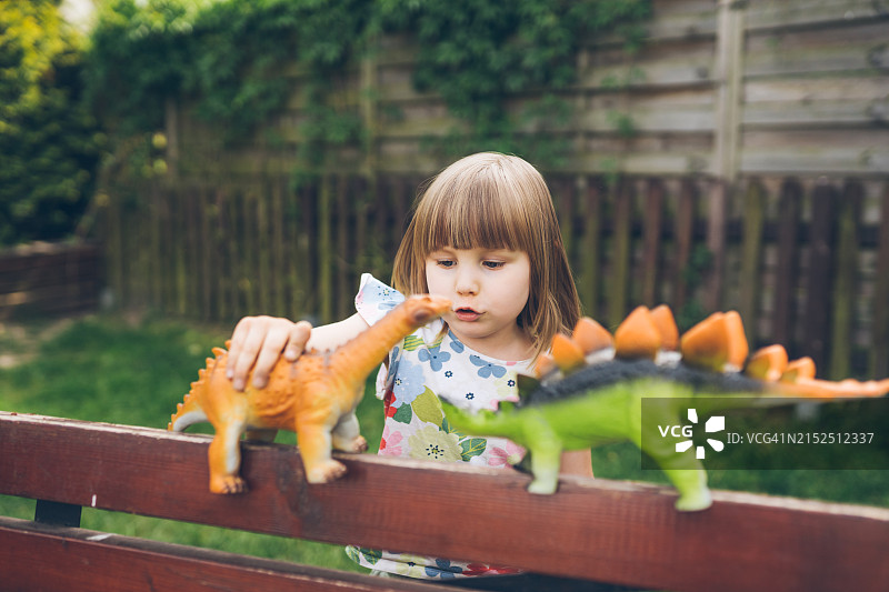 快乐地玩恐龙玩具的可爱女孩图片素材