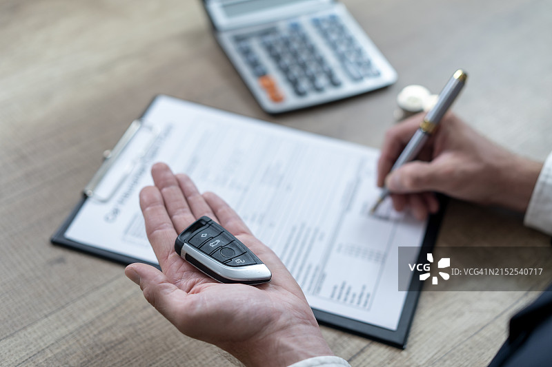 汽车经销商在展厅将车钥匙交给新车主图片素材