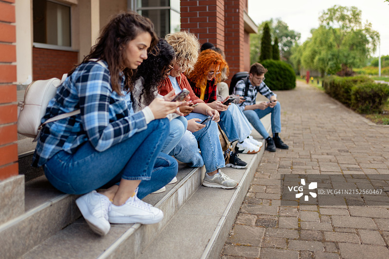 千禧一代大学生在大学休息时使用智能手机图片素材