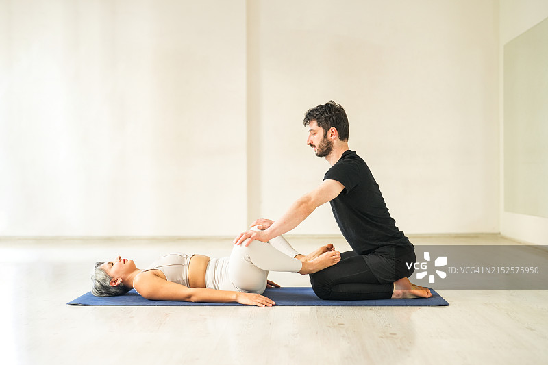 男瑜伽老师指导女学员进行拉伸运动图片素材