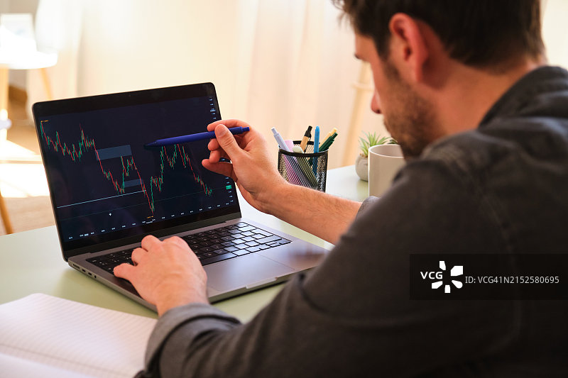 一个男人正在使用笔记本电脑分析股市趋势。图片素材