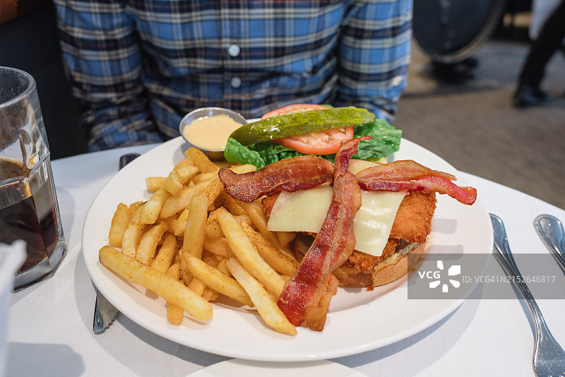 男人在餐厅吃鸡肉三明治和薯条图片素材