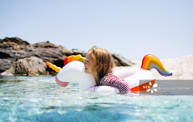 晴天在海边用独角兽浮圈游泳的小女孩图片素材