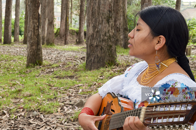在音乐日，一位穿着传统服装的厄瓜多尔印第安妇女充满感情地演奏曼陀林并闭着眼睛唱歌的肖像，留有复制空间图片素材