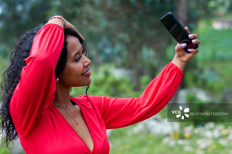 在山上自拍的穿红色连衣裙的年轻拉丁裔女子图片素材