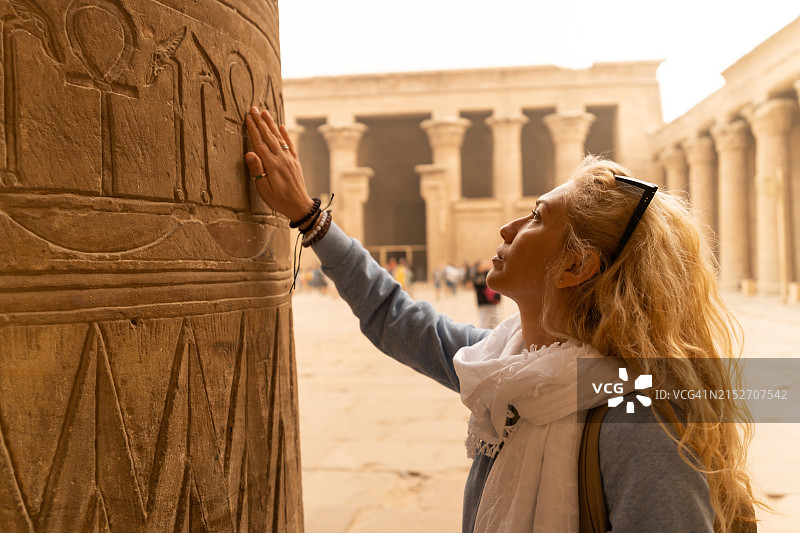 女游客触摸埃及埃德富荷鲁斯神庙的柱子图片素材