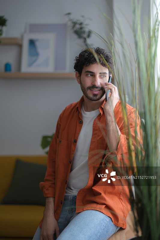 一边用手机通话一边望向窗外的年轻男子肖像图片素材