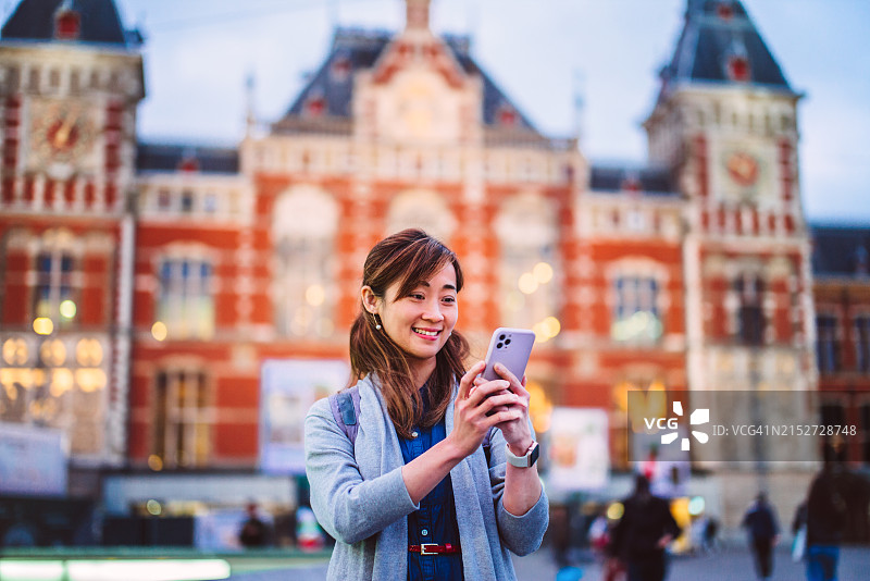 年轻亚洲女性使用手机App导航，在新城市探索地标图片素材