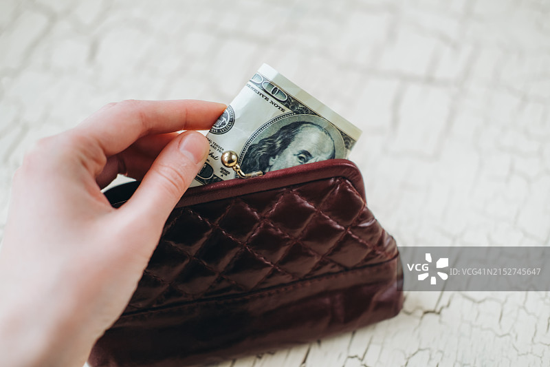 女人从钱包里拿出一张100美元图片素材