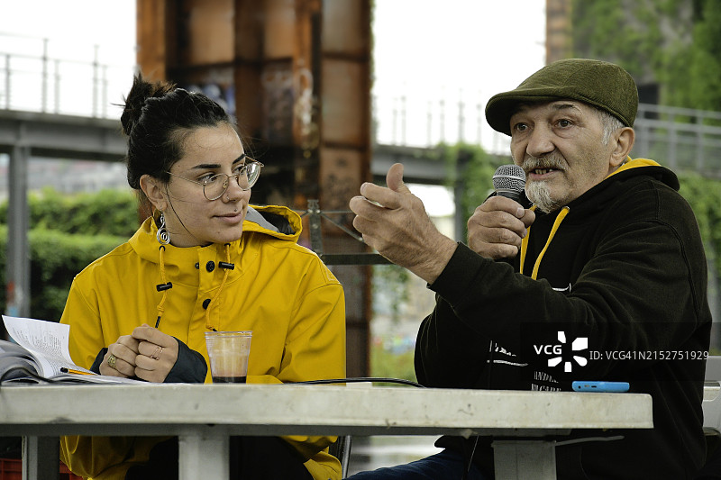 年长的男人向观众讲述他的书，一个女孩在听图片素材