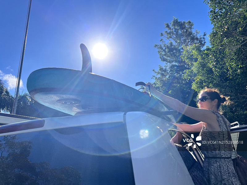 女人将立式桨板固定在陆地车辆顶图片素材