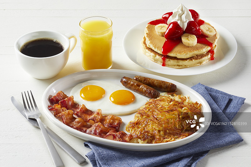 美式早餐：薄煎饼、鸡蛋、土豆饼、培根、香肠、咖啡和橙汁图片素材