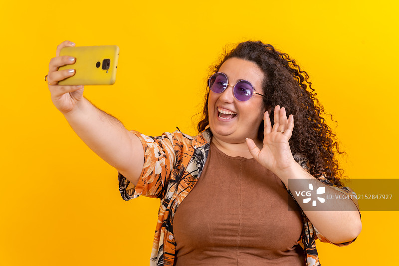 超重妇女在使用手机进行视频通话时向摄像头挥手图片素材