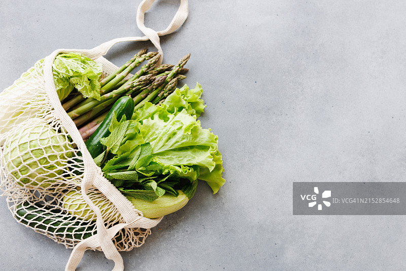 灰色背景下可重复使用的购物袋中的新鲜多汁的绿色蔬菜图片素材