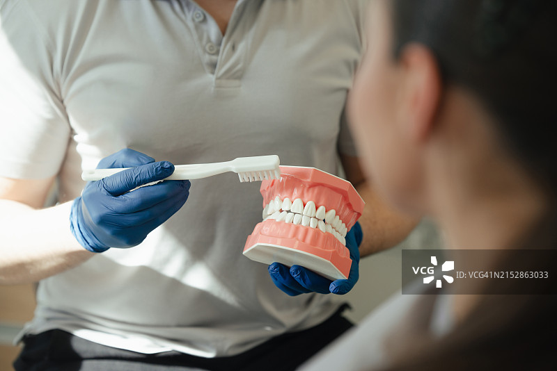 医生讲解洁牙技巧，女患者在牙科诊所接受牙医检查和口腔卫生指导图片素材
