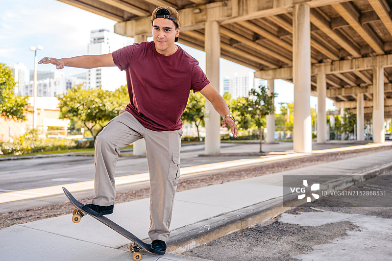 年轻的西班牙裔男子在美国迈阿密的停车场玩滑板图片素材