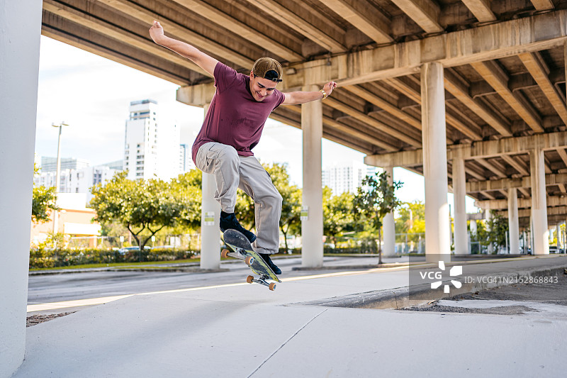 年轻的西班牙裔男子在美国迈阿密的停车场玩滑板图片素材