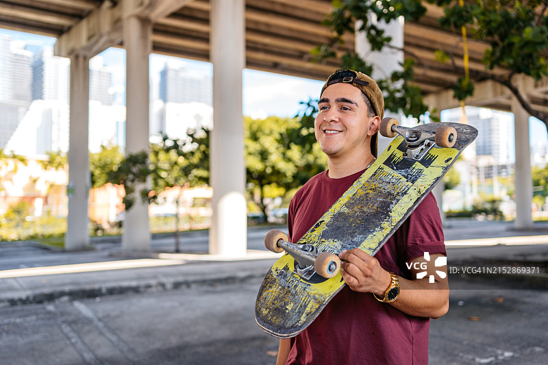 在美国迈阿密停车场，年轻的西班牙裔男子拿着滑板图片素材