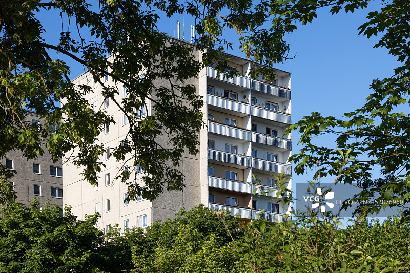 透过树木看到的现代住宅楼阳台图片素材
