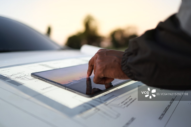 工程师在户外车辆引擎盖上使用平板电脑的背面特写图片素材