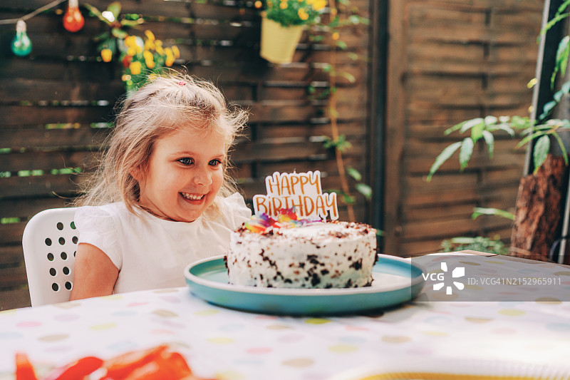 快乐可爱的小女孩吹生日蛋糕蜡烛图片素材