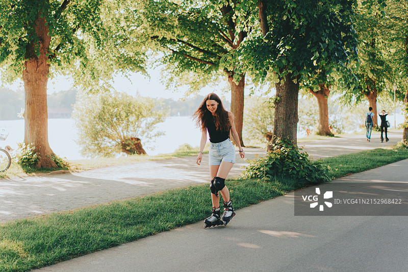 快乐的年轻女人在春日公园里滑旱冰图片素材