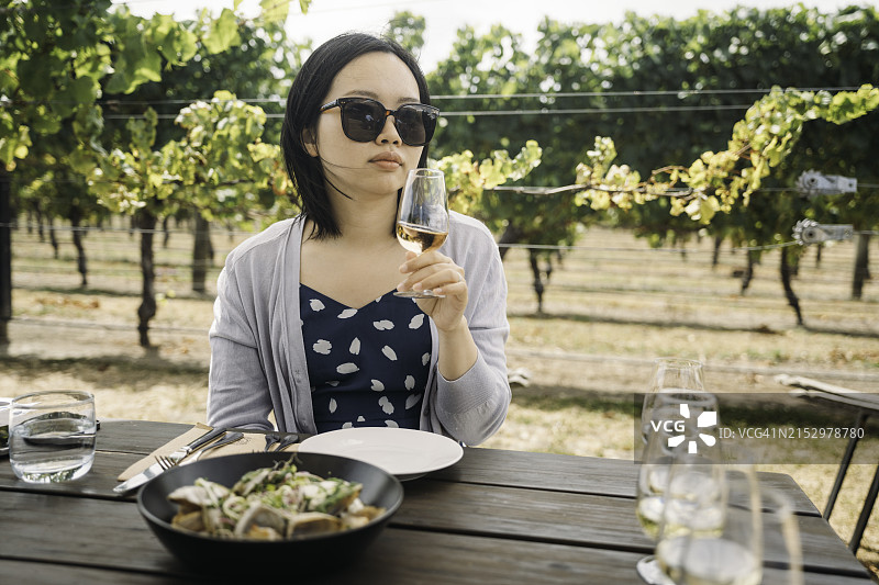 亚洲女游客在户外酒庄品尝葡萄酒的香气图片素材