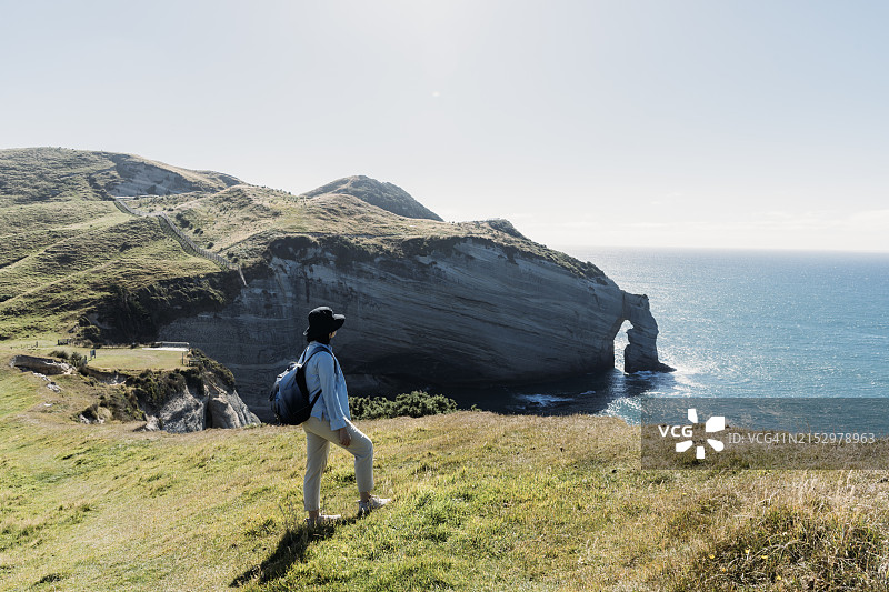 独自旅行的女子站在悬崖边凝视大海图片素材