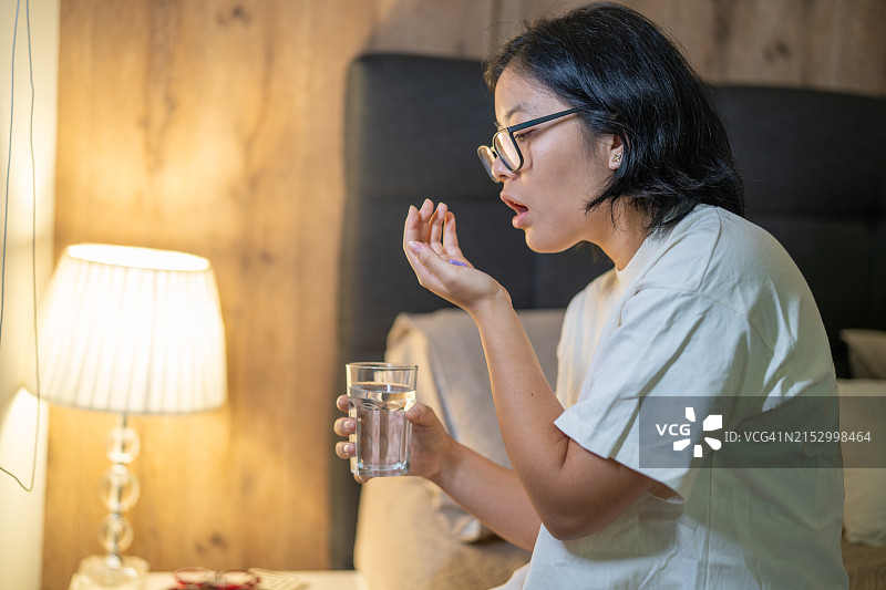 夜晚房间里服用安眠药的疲惫女人图片素材