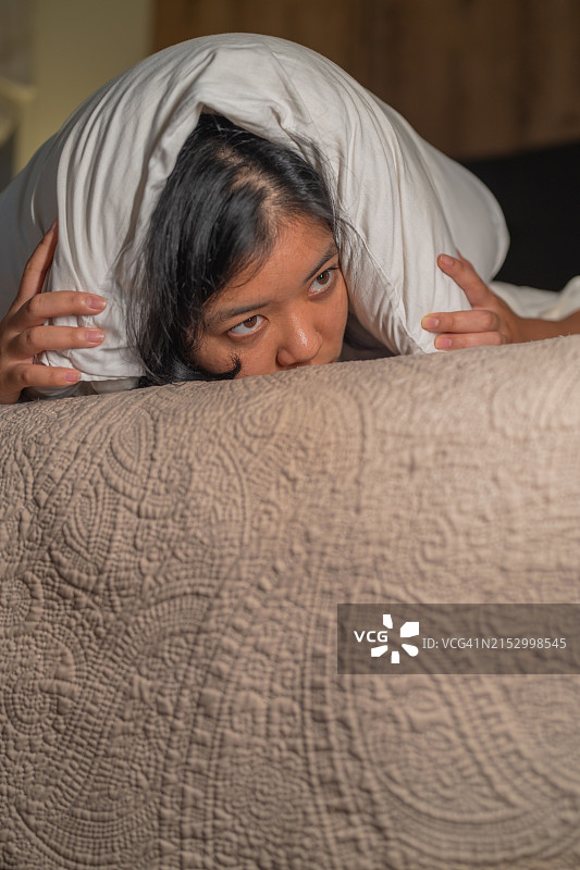 受惊的女人晚上用枕头捂住头图片素材