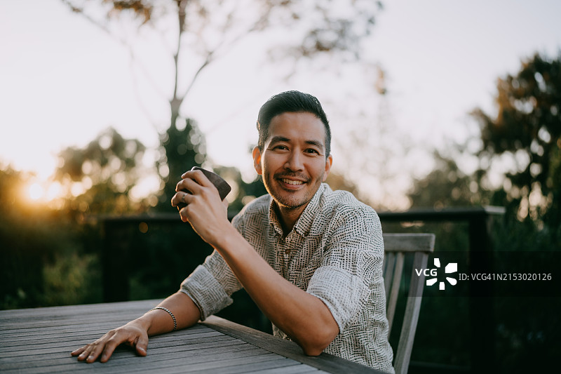 男人在露台上对着日落时的镜头微笑图片素材