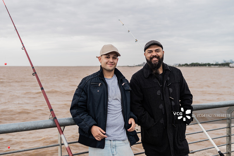 父亲和儿子在阿根廷拉普拉塔河钓鱼的合影图片素材