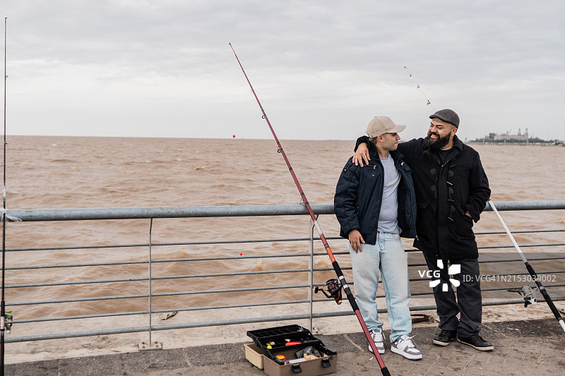 父子在阿根廷拉普拉塔河钓鱼时拥抱交谈图片素材