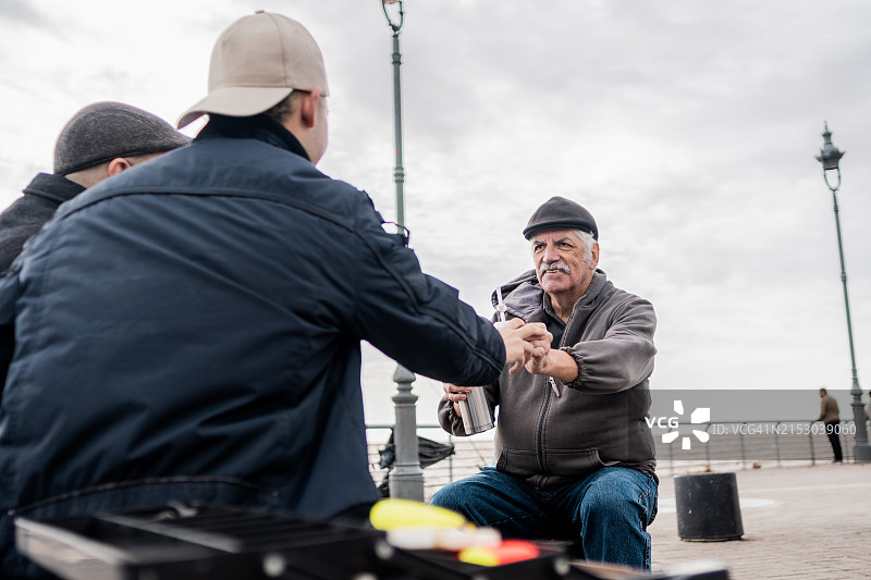 在户外钓鱼日给孙子马黛茶的年长男人图片素材