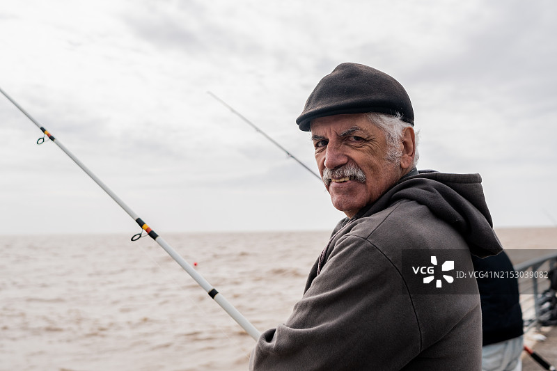 在阿根廷拉普拉塔河钓鱼的老年男人肖像图片素材
