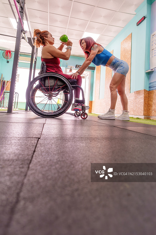 残疾妇女在健身房与私人教练一起锻炼图片素材