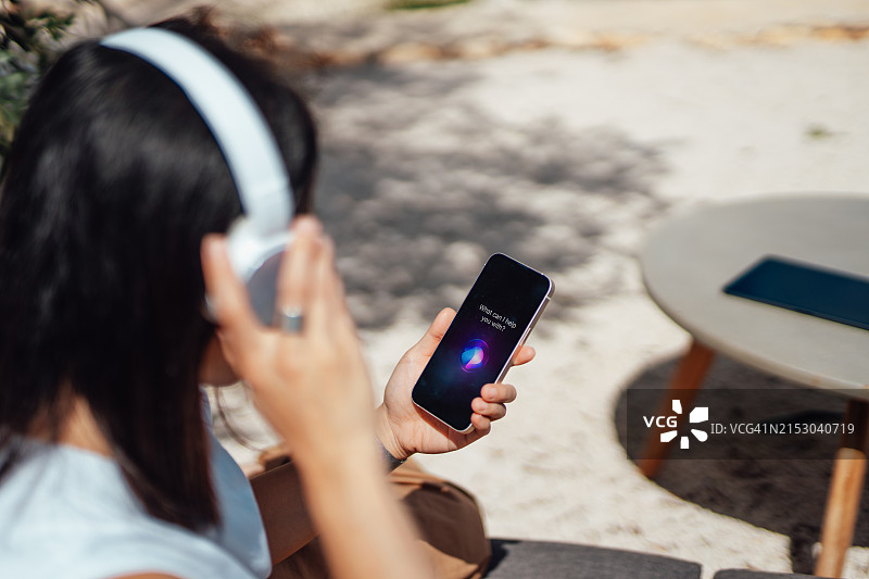 年轻女人在户外使用手机上的AI助手应用图片素材