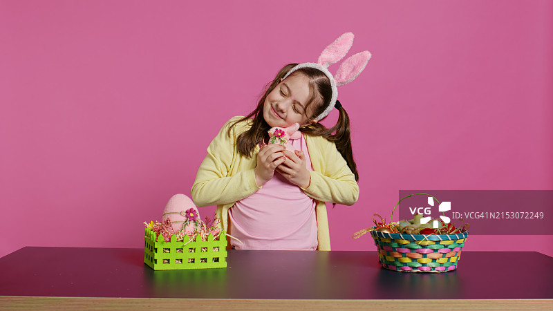 戴着发带，拿着复活节彩蛋的可爱女孩肖像，粉色背景图片素材