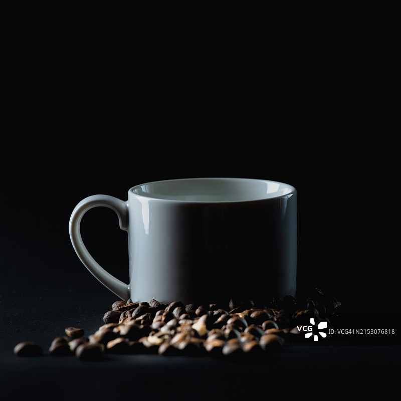 黑色背景上带有咖啡豆的咖啡杯特写图片素材