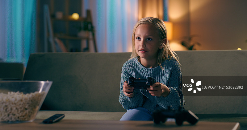 女孩在沙发上玩游戏吃爆米花图片素材